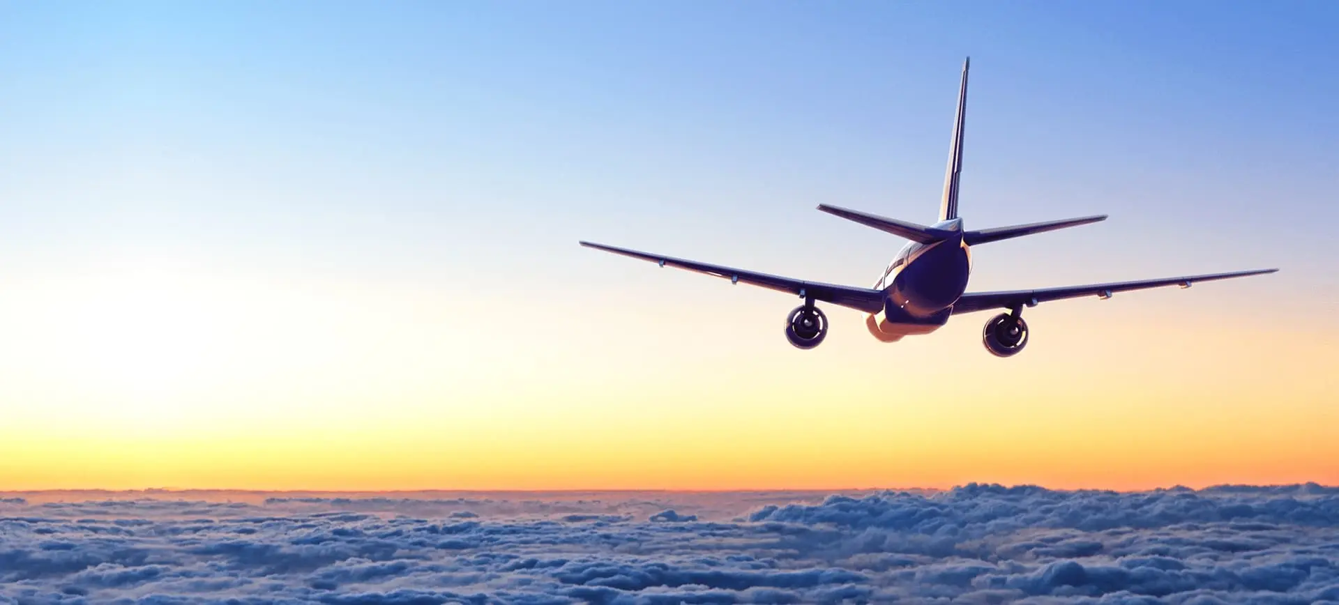 Natural Pharmaceuticals Melatonina Lėktuvas skrenda virš debesų saulėlydžio metu, fone ryški mėlyna ir oranžinė dangaus spalva.